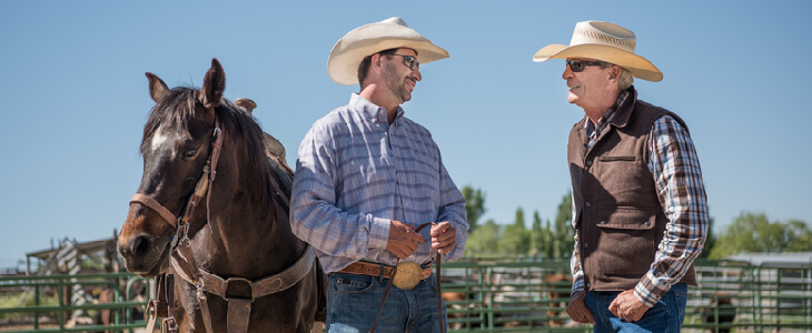 Two horse owners discussing the sale of a horse on a sunny day