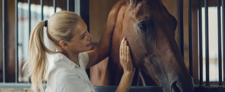 Woman in a barn with her horse.